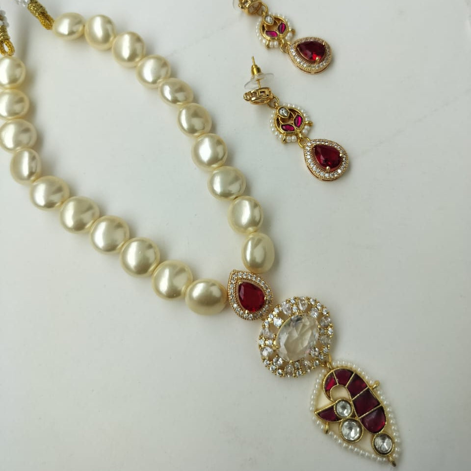 Pearl necklace with gold and red accents on a white background