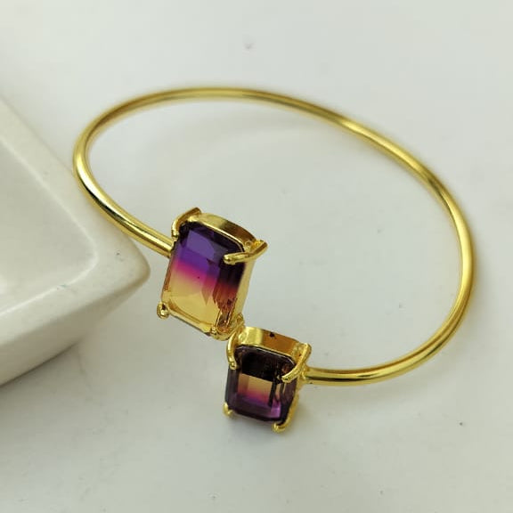 Gold bracelet with a colorful gemstone on a white background