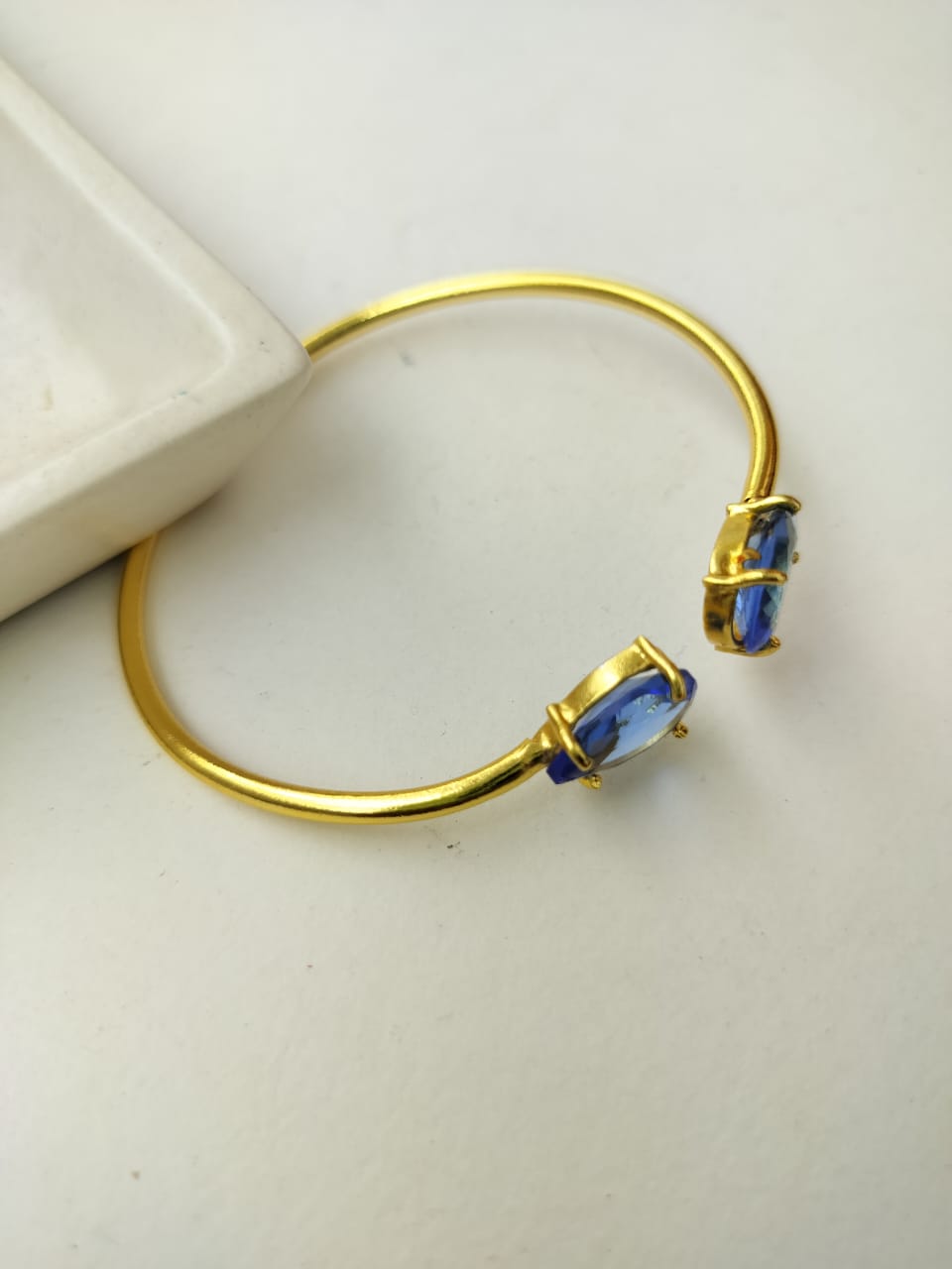Gold bracelet with blue stones on a white background