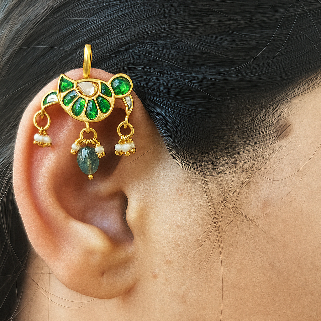 Gold and green ear cuff worn by a person with dark hair.