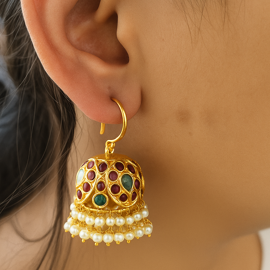 Gold earrings with pearls and gemstones worn by a person