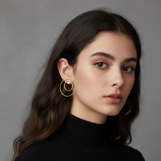 Woman wearing gold hoop earrings against a gray background