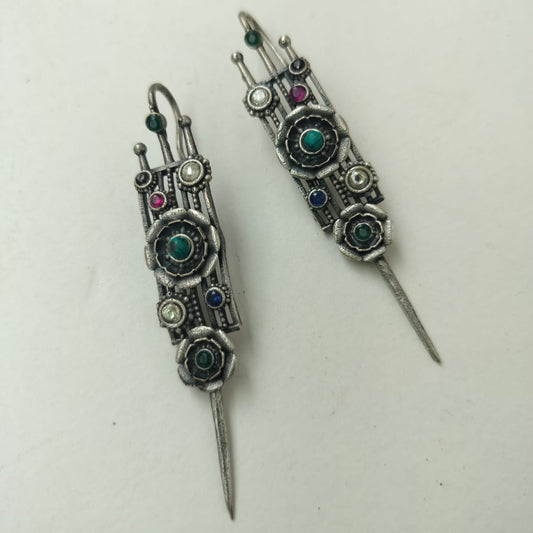 Pair of ornate silver earrings with gemstones on a white background