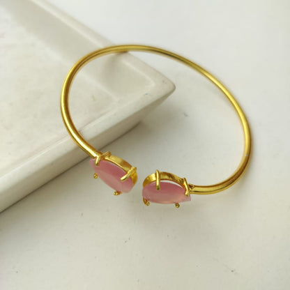 Gold bracelet with pink stones on a white surface