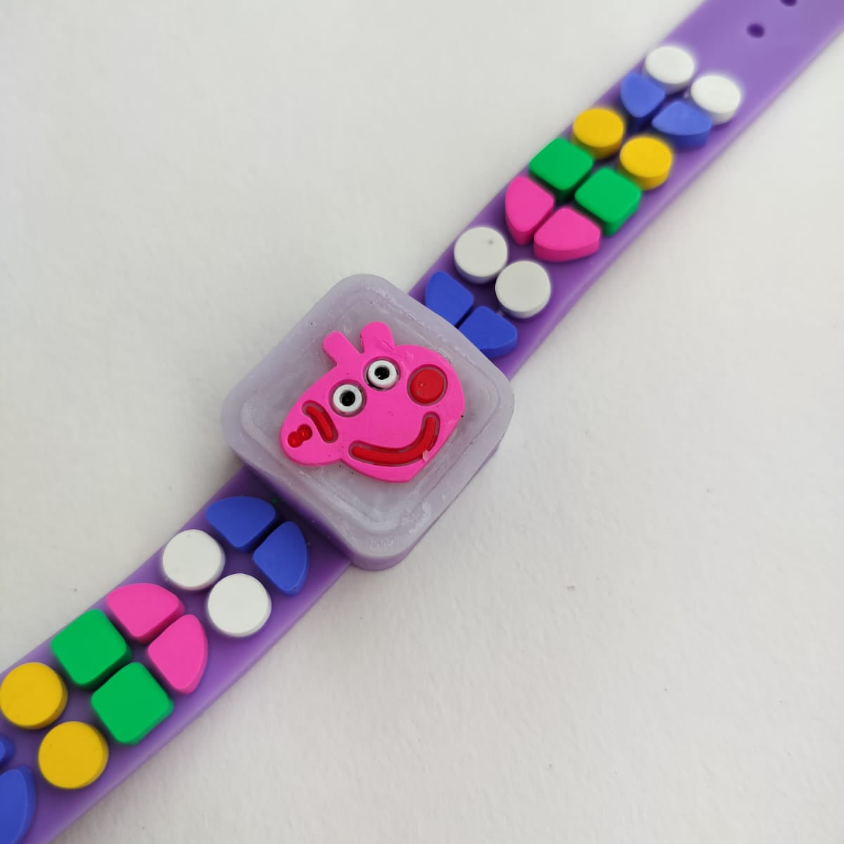 A purple silicone watch strap decorated with colorful round beads and a pink Peppa Pig charm in the center, shown on a plain light background.
