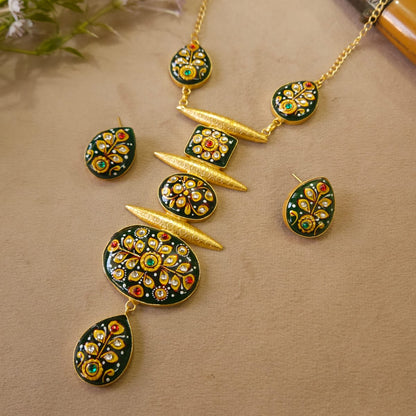 Gold necklace with green and red gemstones on a beige surface