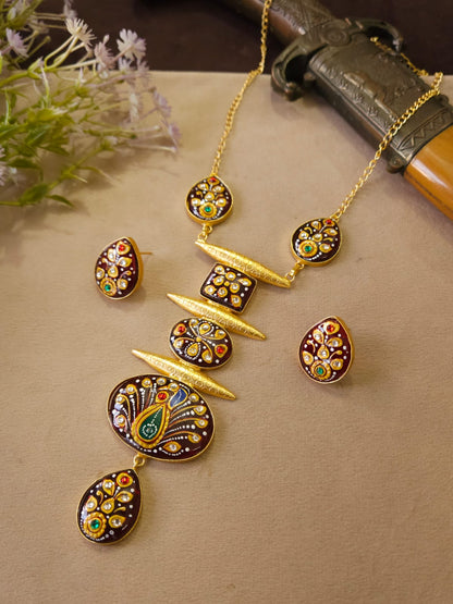 Gold jewelry set with peacock design on a beige surface