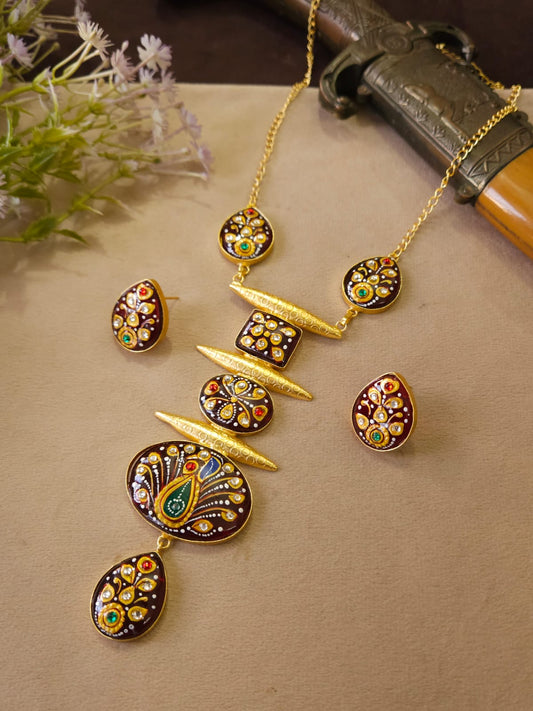 Gold jewelry set with peacock design on a beige surface