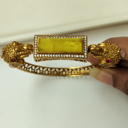 Gold bracelet with a rectangular gemstone held against a white background